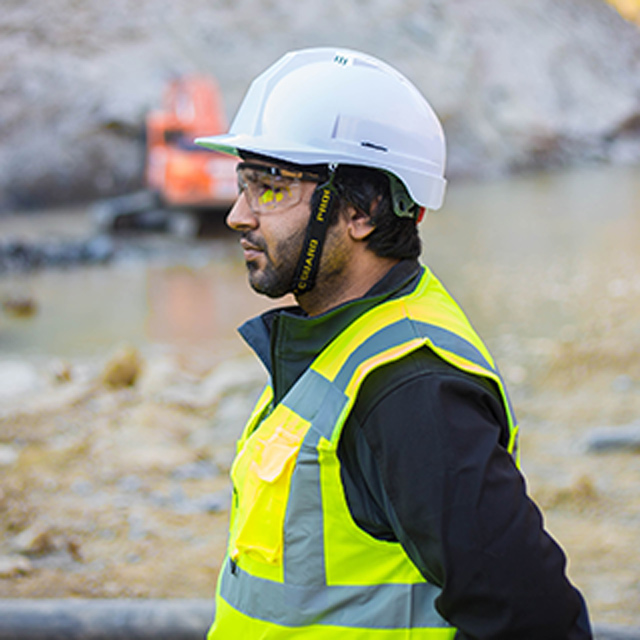 Person At Construction Site Wears Safeety Glasses And Hard Hat