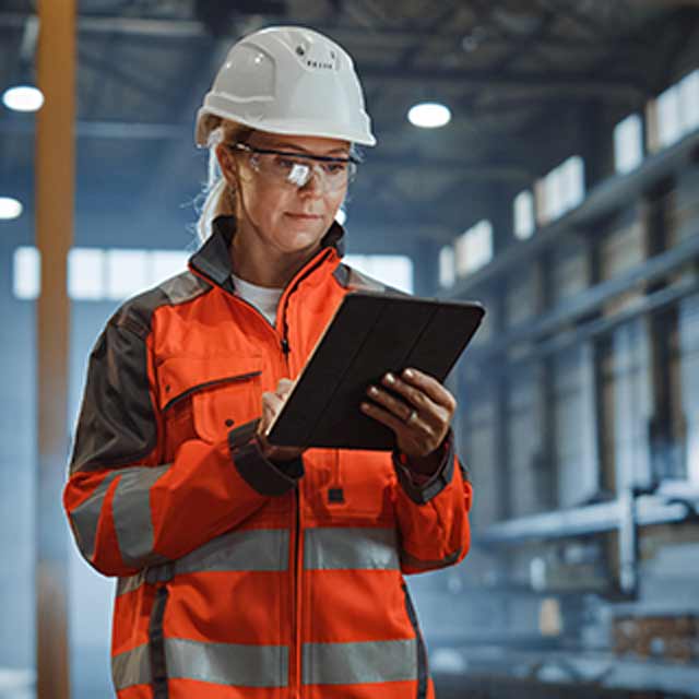 Person Looks At Tablet While Wearing Hard Hat And Glasses